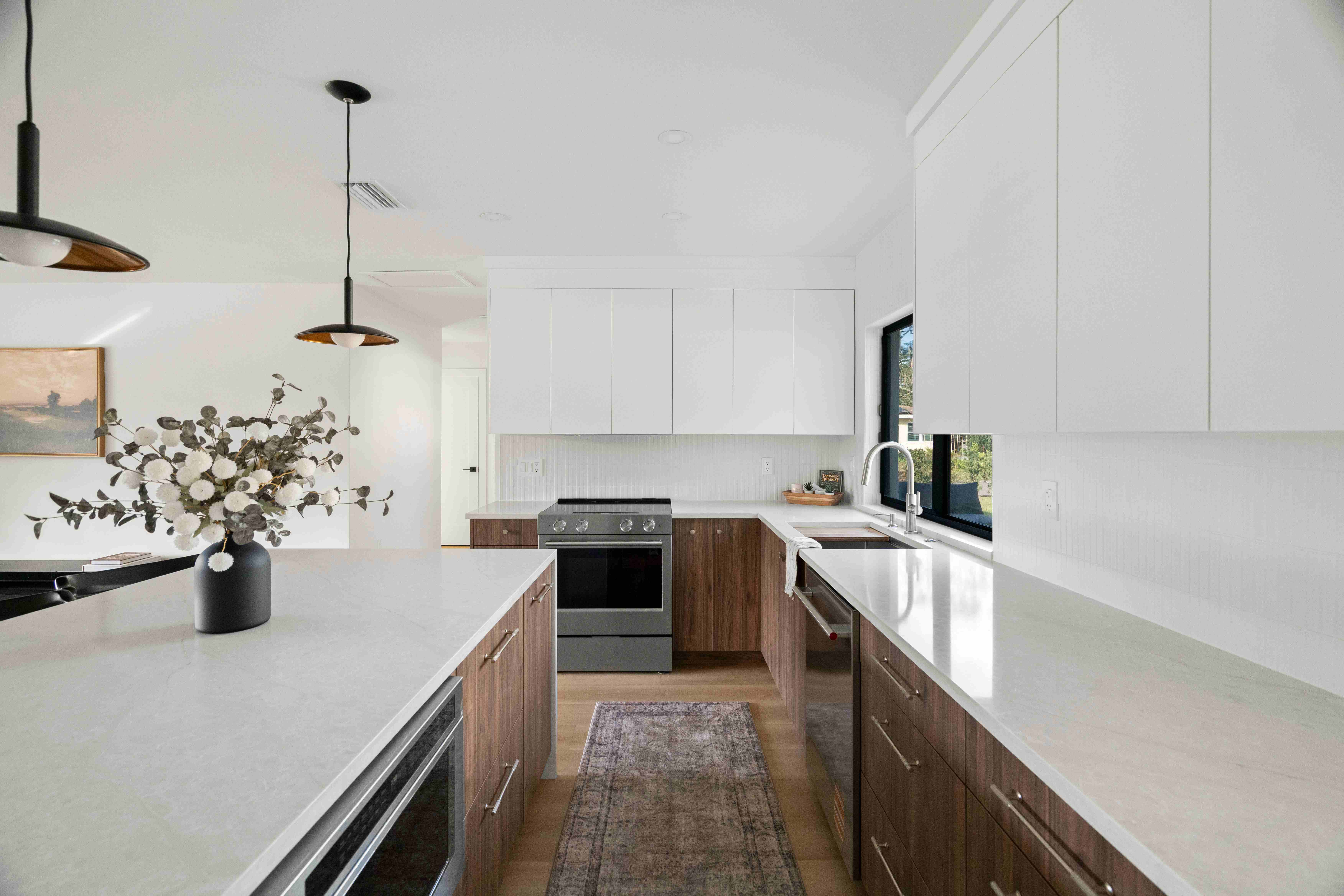 Modern renovated kitchen with white countertops and warm walnut cabinets